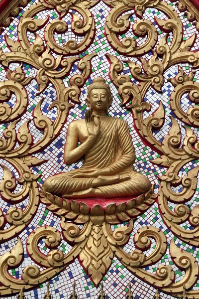 20151102, Vang Vieng, Laos : Porta de entrada ornamentada com relevos dourados. O Buda Ensinante retrata um momento particular na vida do Buda, a saber, o primeiro sermão que o Buda fez depois de alcançar a Iluminação. de Unbekannt