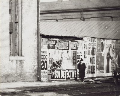 Um homem passa por uma parede de anúncios em pôster, incluindo um de Johnnie Hoey, o detetive do menino, no Havlin&39;s Theatre em Walnut Street, 600 de Unbekannt