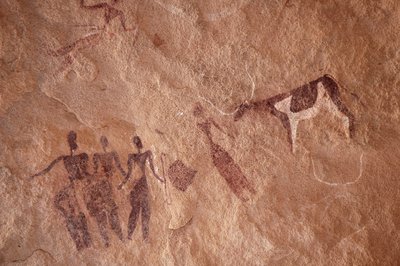 Arte rupestre, Pré-história: Pintura rupestre de um grupo de personagens e uma vaca de duas cores com chifres grandes num abrigo ornamentado, no maciço de Uweinat, Egipto. (Período de 8000 a 3000 anos a.C.). Fotografia de Unbekannt