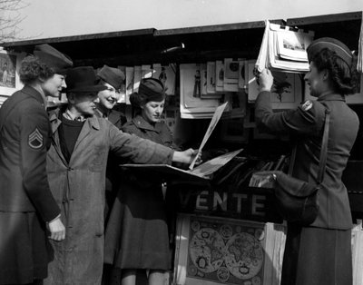 Segunda Guerra Mundial (1939-1945) - Segunda Guerra Mundial (II Guerra Mundial ou 2ª Guerra Mundial): Paris (França), Março de 1945: Quatro Wacs (Women Army Corps) do Exército dos EUA discutem com uma jogadora de livros nas margens do Sena. de Unbekannt