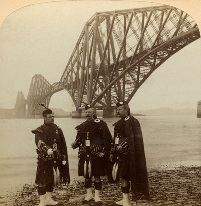 Homens de Highland se vestem em frente à Forth Bridge, na Escócia. de Underwood and Underwood