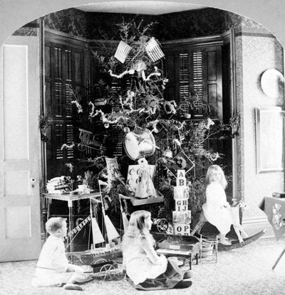 Crianças reunidas aos pés da árvore rodeadas de presentes na manhã de Natal. de Unknown photographer