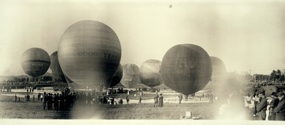 Balões de ar quente em um campo em South St. Louis prontos para lançamento; um já está no céu à distância de W.C. Persons
