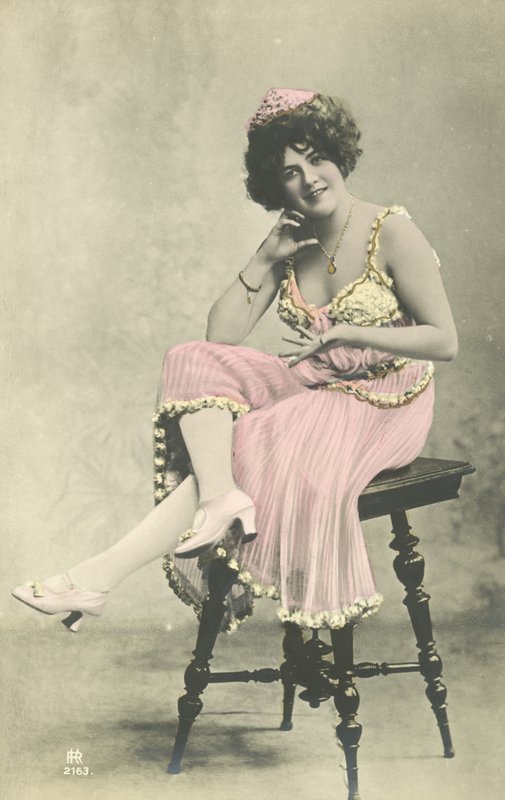 Atriz, com sorriso bonito, em vestido rosa sentado no banquinho de French Photographer