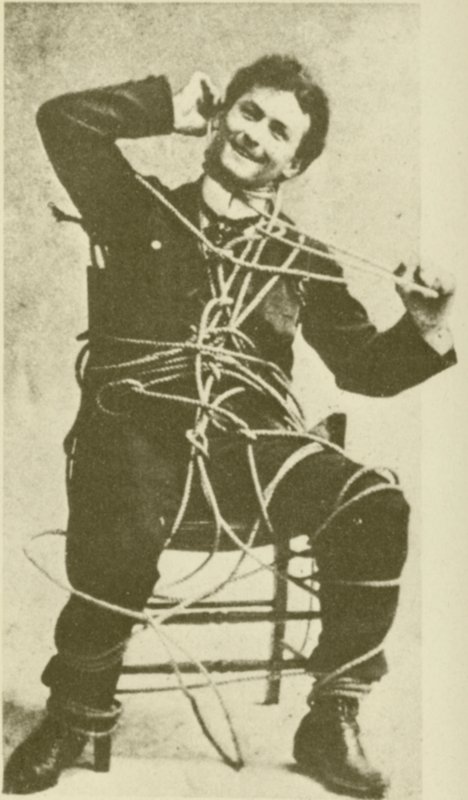 O jovem Harry Houdini a fazer um truque de fuga à corda em 1898 (fotografia a preto e branco) de American Photographer