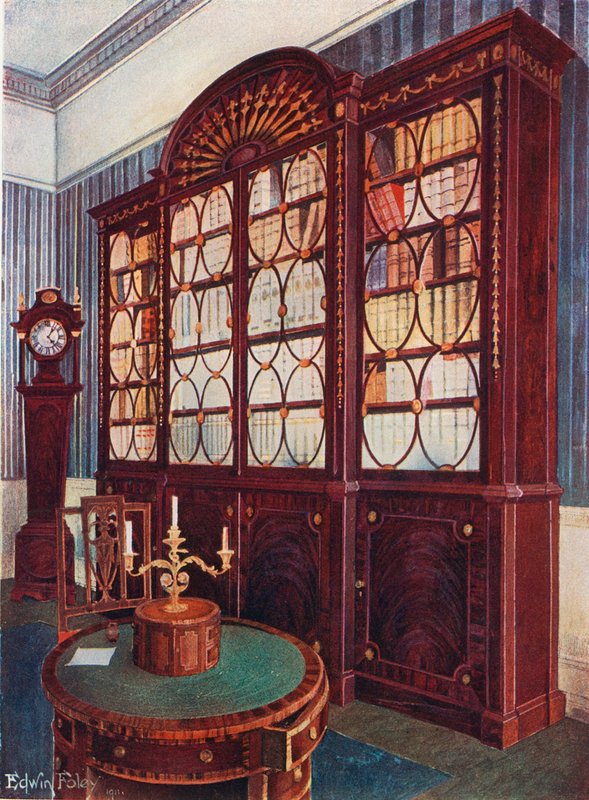 Estante embutida em mogno. Mesa de centro de pedestal de mogno. Relógio de mogno alto de Edwin John Foley