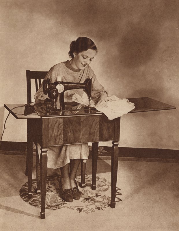 Dona de casa a trabalhar na máquina de costura, meados dos anos 30 (fotografia a preto e branco) de English Photographer