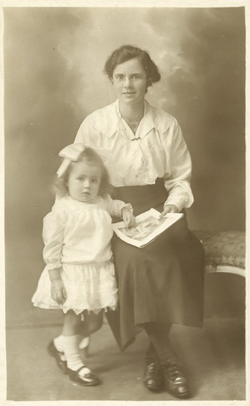 Menina bonita, mãe ou governanta, mostrando fotos para criança pequena (foto a p/b) de English Photographer