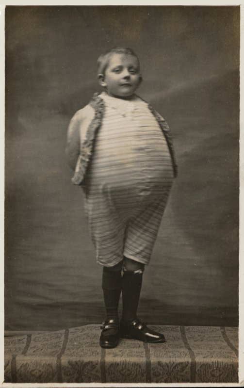 Menino de escola, vestido para ter um estômago muito grande (foto a p/b) de English Photographer