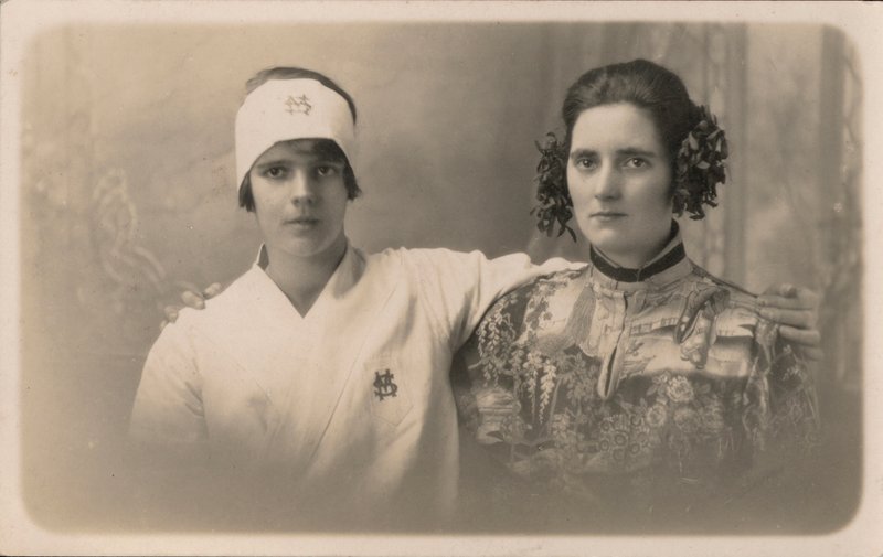 Duas jovens mulheres, com os braços à volta dos ombros uma da outra (fotografia a preto e branco) de English Photographer