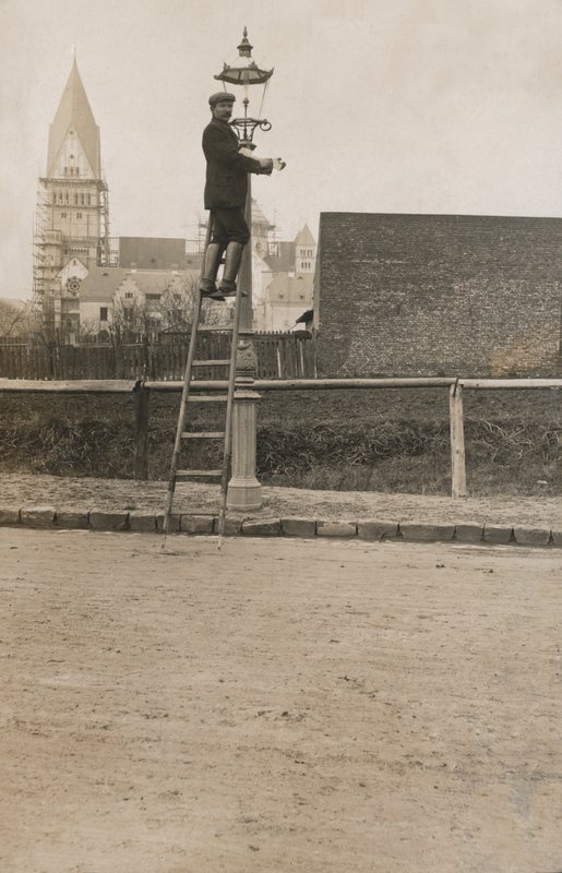 Homem a subir uma escada fixando um candeeiro de rua (foto a p/b) de European Photographer