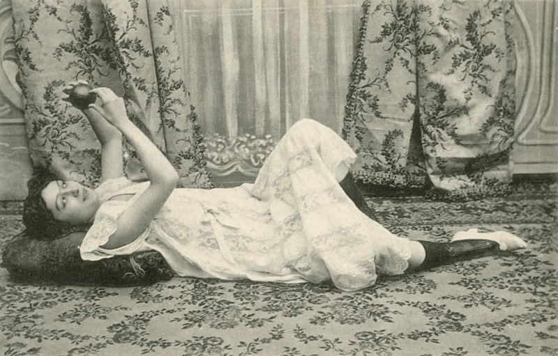 Menina, deitada no chão, segurando uma bola acima da cabeça (foto a p/b) de French Photographer