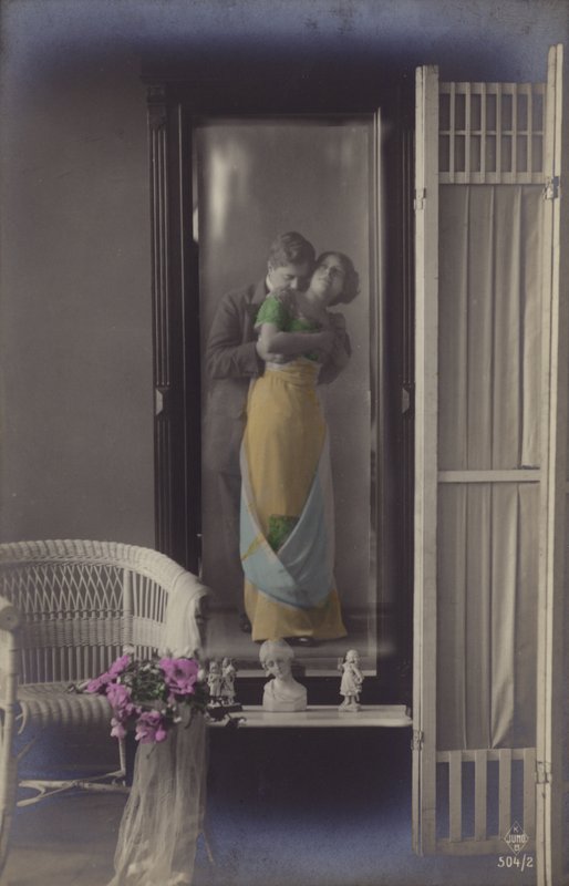 O reflexo em um espelho de um jovem casal se beijando (foto matizada) de French Photographer