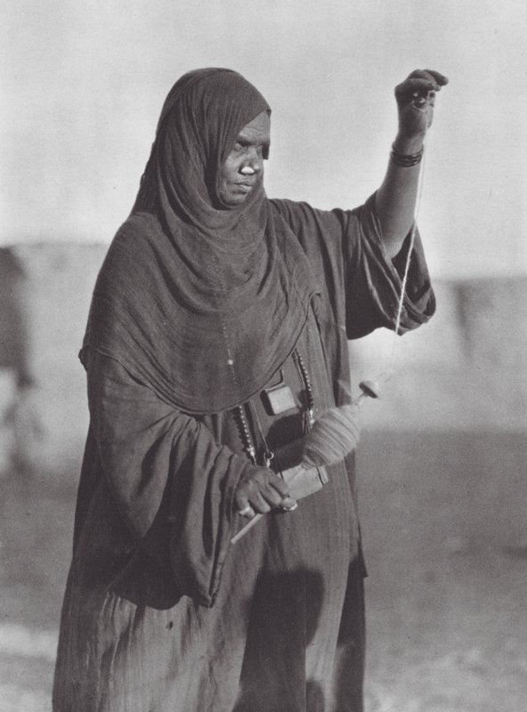 África: Mulher Bisharin a fiar, deserto da Núbia (fotografia a preto e branco) de Hugo Adolf Bernatzik