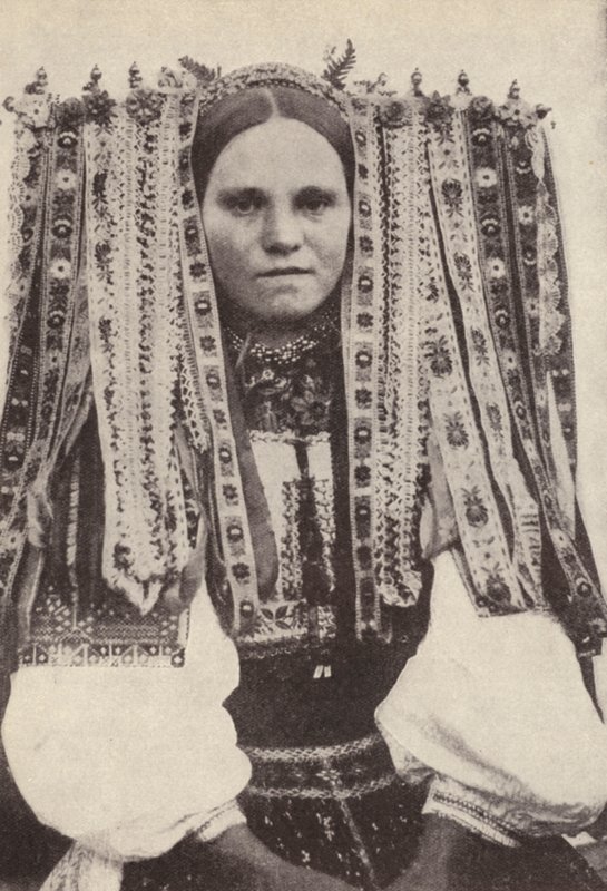 Mulher tcheca usando um cocar de fitas onde cada fita denota um pretendente que ela recusou em casamento (foto a p/b) de Photographer Czech