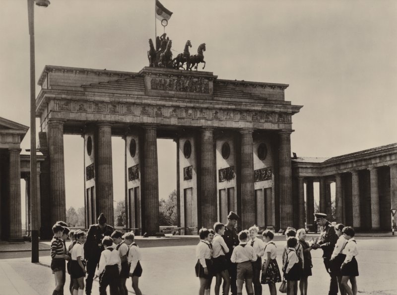 Os pioneiros de Yong vêm ao Portão de Brandenburgo, o marco de Berlim, para ver seus amigos, os guardas da fronteira (foto a p/b) de Photographer German