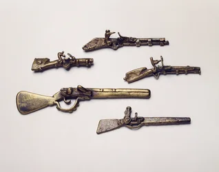 Pesos de ouro moldados em forma de armas (latão)