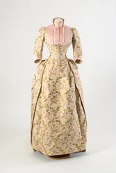 Vestido de seda castanho claro tecido com um desenho de malva, flores azuis e amarelas e folhas verdes, painel e punhos de seda com nervuras rosa claro