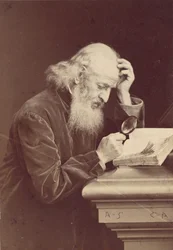 [Homem barbudo com lupa examinando um manuscrito], década de 1870.
