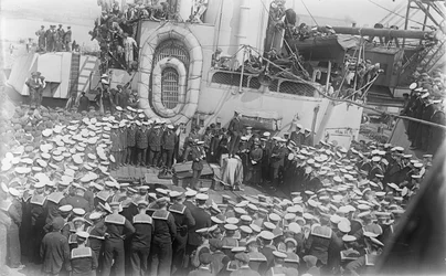 Multidão de marinheiros em torno do primeiro-ministro australiano, o Hon William Morris (Billy) Hughes, enquanto se dirige a eles no convés da HMAS Austrália, no estaleiro de Devon, Inglaterra, em 21 de maio de 1916