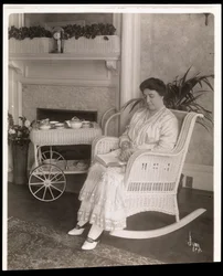 Sra. Howard sentada com um livro em uma cadeira de balanço em sua casa em 200, 5th Avenue, Nova York, 1915-6 (impressão em gelatina de prata)