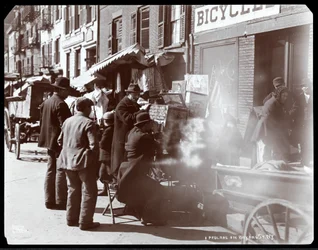 Vista de vendedores de rua, incluindo um que está mostrando visões fotográficas de lugares exóticos em uma caixa de visão, em Bayard Street, Nova Iorque, 1898 (impressão de gelatina de prata)