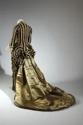 Vestido de noite, c.1884 (vista oblíqua das costas). Cetina de seda e veludo cortado, renda, borlas de fio de seda e franja. Charles Frederick Worth, França.