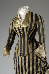 Vestido de noite, c.1884 (vista parcial oblíqua lateral). Cetina de seda e veludo cortado, renda, borlas de fio de seda e franja. Charles Frederick Worth, França.