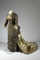 Vestido de noite, c.1884 (vista lateral oblíqua). Cetina de seda e veludo cortado, renda, borlas de fio de seda e franja. Charles Frederick Worth, França.