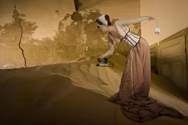 Mulher vintage a passar roupa na areia