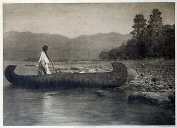 Índios da América: um índio num barco de canoa no Lago Flathead do sul, Montana