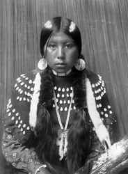 Mulher indiana Kalispel, riscas brancas pintadas no cabelo, brincos de disco de concha, vestido de manta decorado com dentes de alce, c. 1910, foto Edward S. Curtis