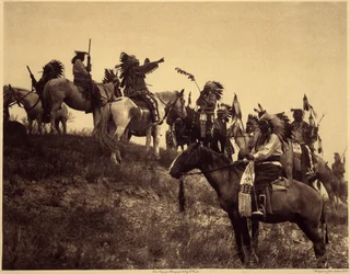 Planear uma rusga. Os índios, com os seus impressionantes trajes típicos, reúnem-se em grupos extremamente pitorescos. Trata-se de uma tropa de Sioux Ogalala (Oglala), numa colina com vista para o Vale de Wounded Knee, na Reserva de Pine Ridge, Dakota do S