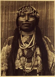 Wishham girl. Esta rapariga está vestida com um pesado vestido de camurça adornado com pérolas. O atributo ornamental indispensável de uma pessoa bem nascida foi a concha dentária no septo nasal. O toucado é feito de conchas, conchas e missangas de lixo, a