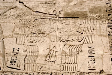 Antiquidade egípcia: detalhe dos relevos da primeira torre representando a captura de combatentes pertencentes aos povos do mar, inimigos de Ramsés III. Templo Funerário de Ramsés III (1187-1156 AC). Luxor, Medinet Habou, Egito.