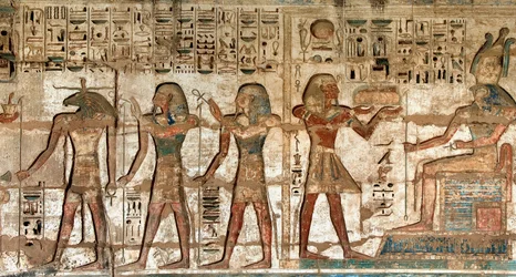 Antiquite egípcio: primeira corte, detalhe de relevos pintados retratando o faraó levando oferendas aos divinitas Horus e Khnoum. Templo Funerário de Ramsés III (1187-1156 AC). Luxor, Medinet Habou, Egito.