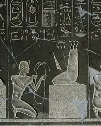 Alívio dolerite de Nectanebo I, rei oferecendo colar ao demônio, representado por lâmina de faca e três cobras, de Heliópolis no templo de Atum.
