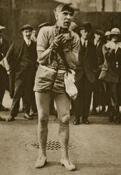 Um ator vestido como Houdini fora de uma porta do teatro (foto sépia)