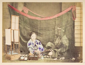 Casal japonês em seu lazer, Quadro de estúdio de uma jovem japonesa, sentada com um impedimento para fazer chá ao seu redor, entregando um cachimbo a uma figura masculina que está sentada atrás dela, protegida por um mosquiteiro de linho,   Fotógrafo: Desc
