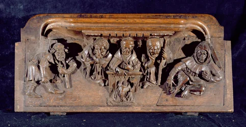 Um misericordioso representando um acadêmico sentado em uma mesa de painel entregando uma admoestação a um penitente ajoelhado, New College Chapel, Oxford, final do século XIV (madeira)