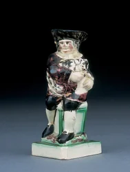 Jarro de Dick Whittington, moldado subindo de uma cadeira de espaldar alto, segurando seu gato, salpicado de roupas marrons, verdes e pretas, um escudo moldado ao lado, c.1790