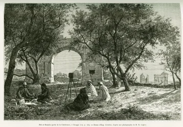 Bab-er-Roumia (Bab er Roumia), porta da mulher cristã, ruínas romanas em Dougga, piquenique de viajantes e dos seus guias em redor de uma máquina fotográfica. Gravura de Eugène Girardet para ilustrar o relato «Voyage en Tunisie», de R. Cagnat e H.