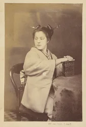[Mulher japonesa sentada segurando um álbum de cartes-de-visite numa mesa]