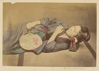 [Mulher japonesa a dormir segurando uma ventoinha].