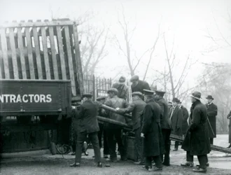 Uma multidão de espectadores espera enquanto um rinoceronte é descarregado de um caminhão, por guardiões, no zoológico de Londres em 1924