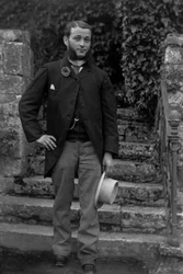 Retrato de um jovem de Bourmont, na Alta Marne, usando a cocarda dos recrutas na botoeira, posando no jardim da abadia de Septfontaines. Fotografia do final do século XIX. Coleção Ducos.