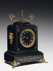 Relógio de manto em pedra de composição preta, com decoração incisa, com pés, remates e guarnições em latão dourado, de Jausions de Pau, França, c.1876-78 (pedra de composição preta, com decoração incisa