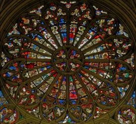 Vitral w217, a rosácea norte, representando a Coroação da Virgem nas duas aberturas superiores, rodeada por anjos com instrumentos musicais e os Instrumentos da Paixão (rosácea)