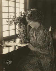 Mary Pickford, usando um quimono, escrevendo numa secretária, c.1918 (foto a p/b)