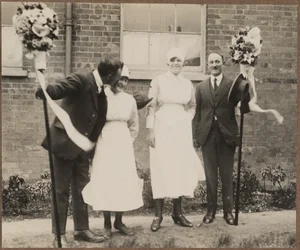 Dois homens segurando bastões de tutti, de pé com duas mulheres durante o Festival Hocktide em Hungerford